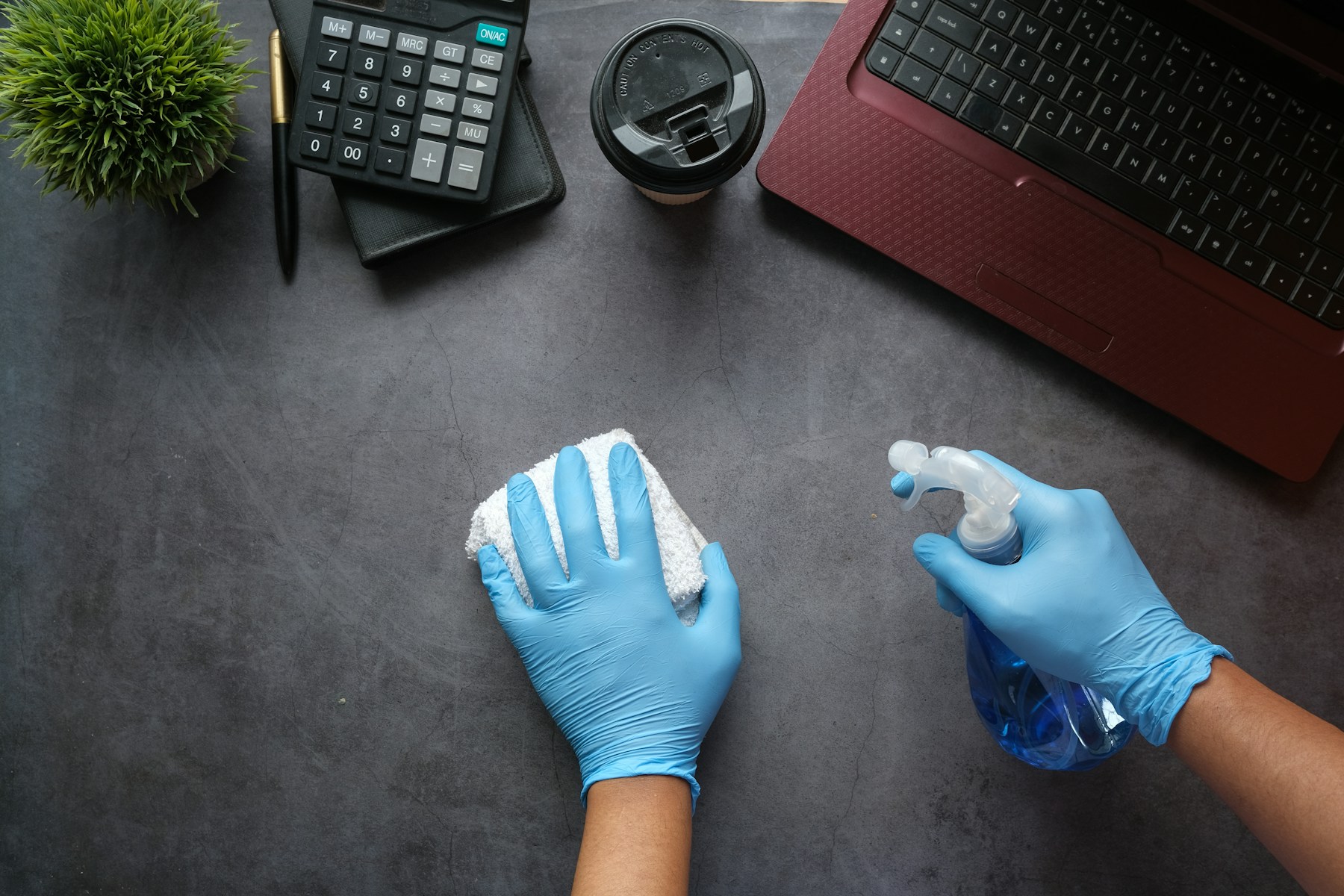 Desk being cleaned with a spray bottle and cloth